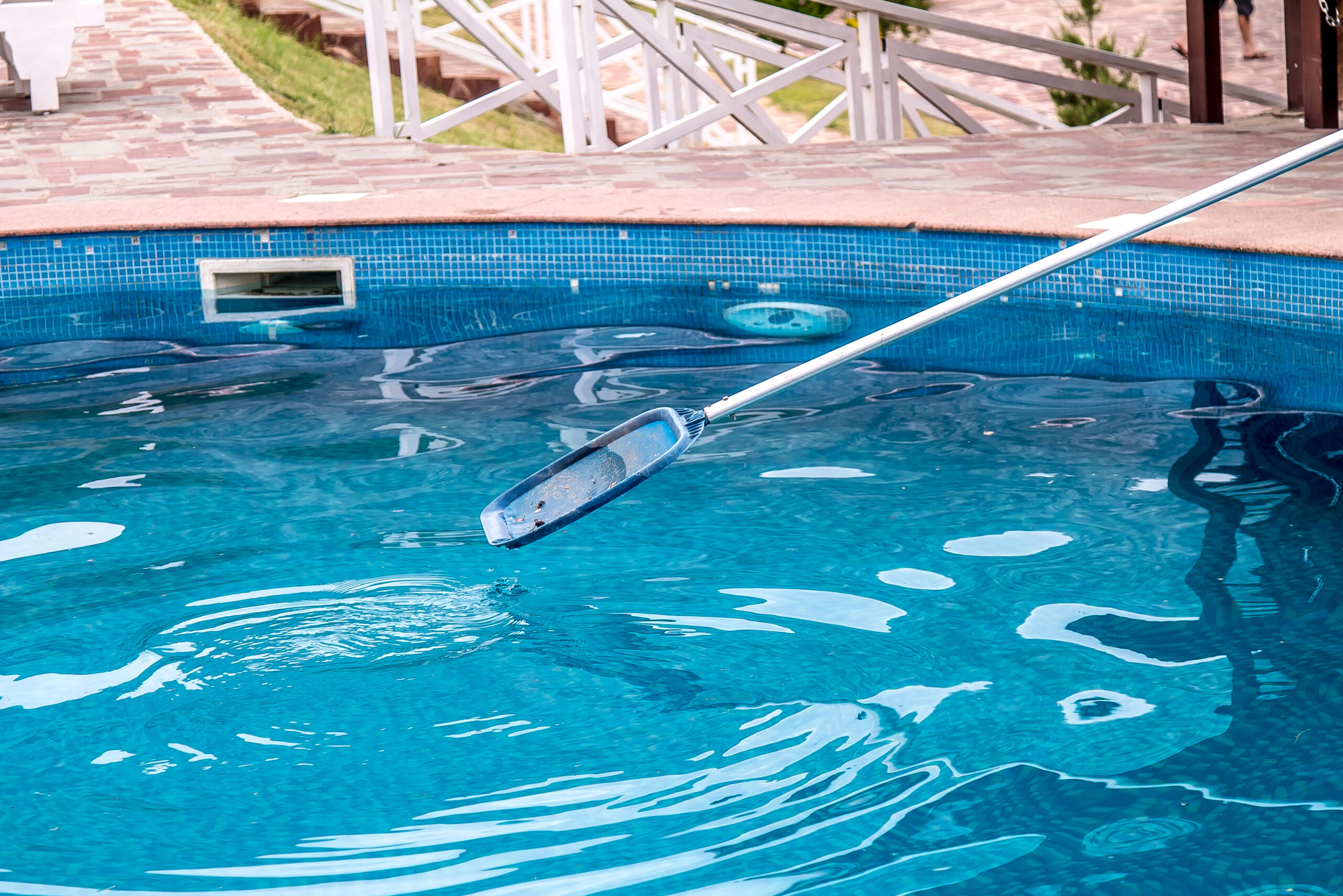 Pool technician cleaning a pool in Pensacola with a vacuum brush